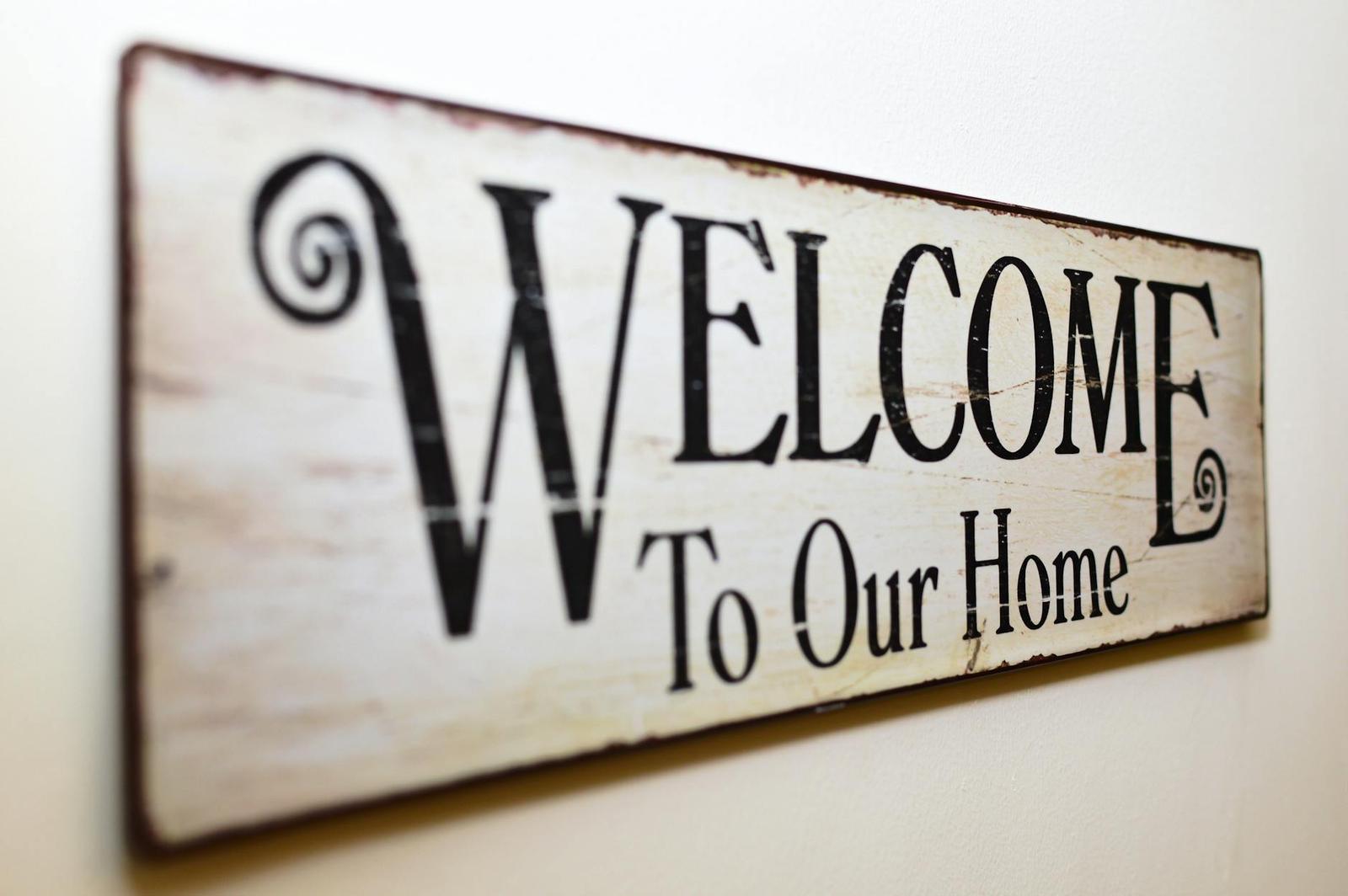 Wooden welcome sign reading welcome to our home on a wall