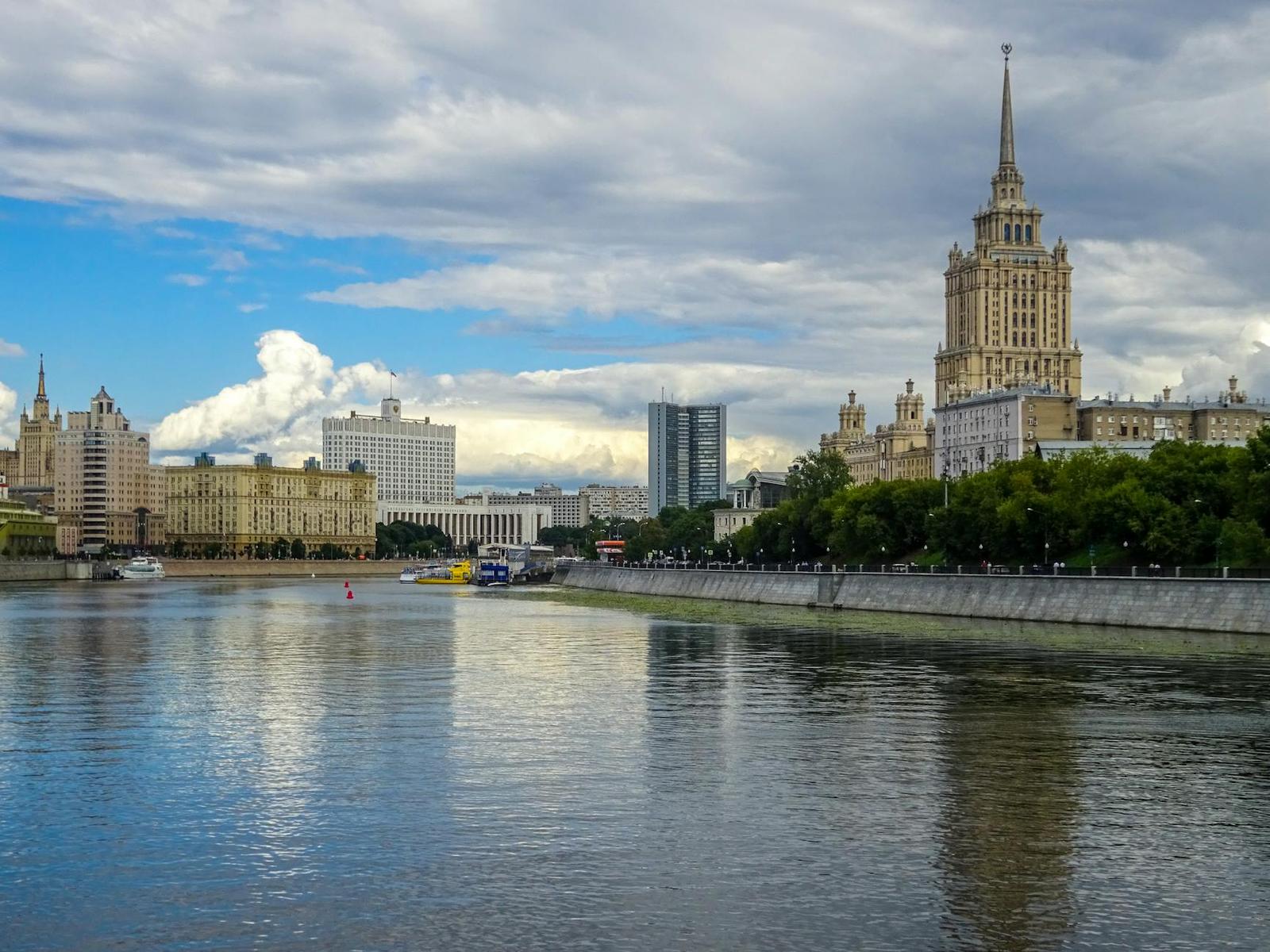 A spired Stalinist-era tower rising above a riverfront skyline under clouds