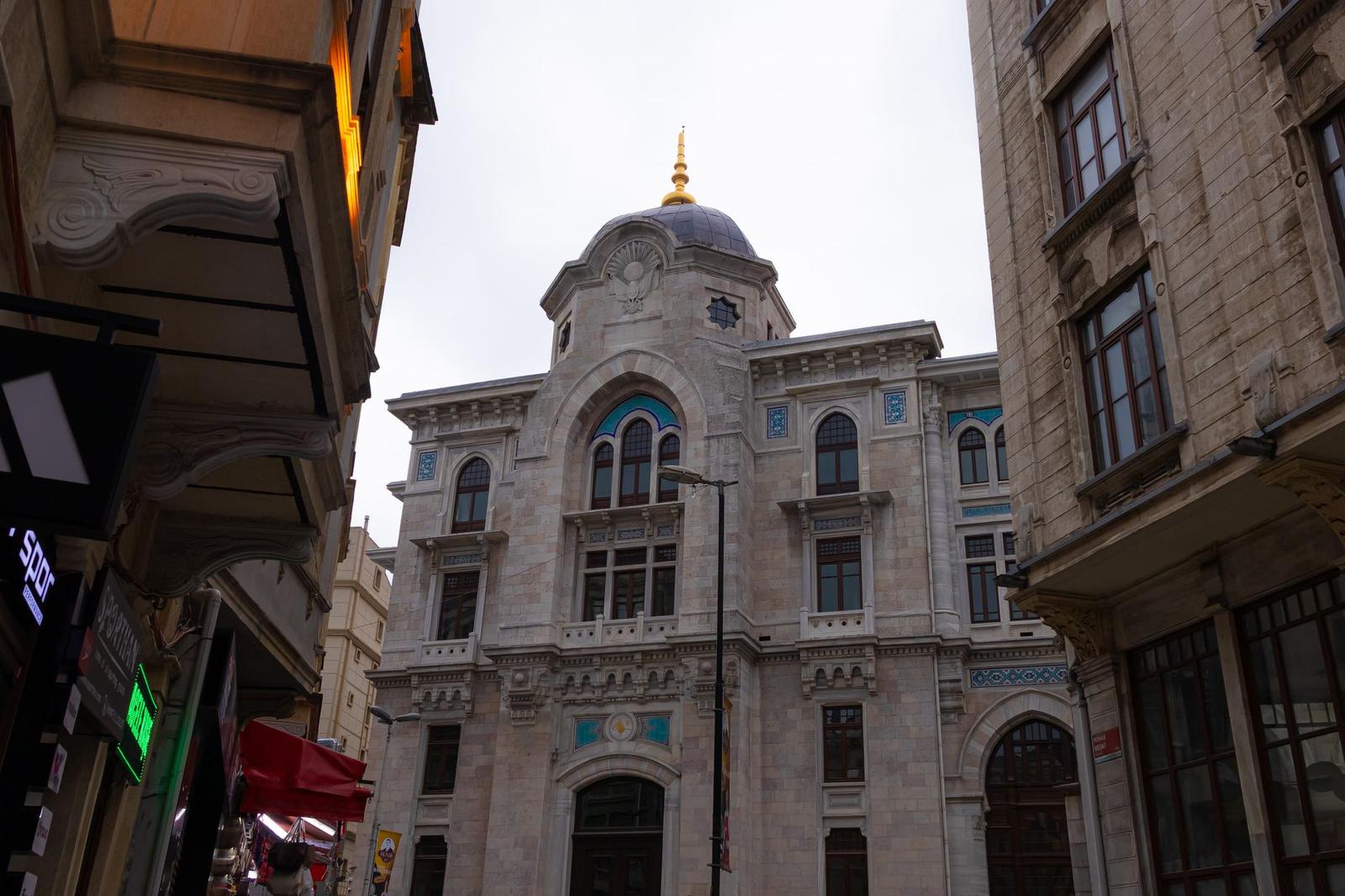 Ornate domed building with a golden spire rising above a narrow street
