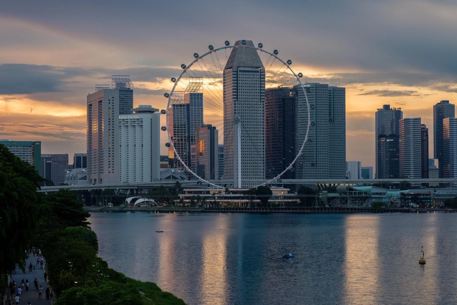 Stunning view of the Singapore skyline with the Ferris wheel at sunset, reflecting over Marina Bay