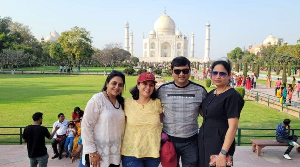 A group posing happily in front of the iconic Taj Mahal.