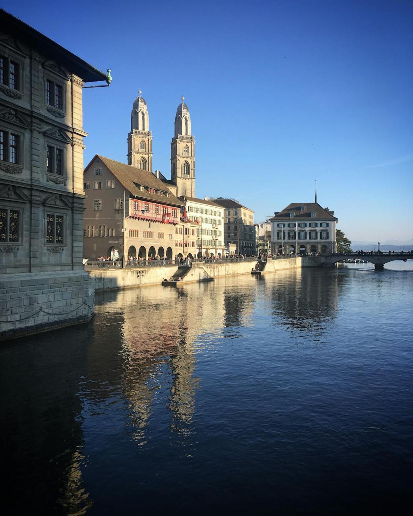 Stunning view of Zurich's Grossmünster reflected in the Limmat River on a clear day