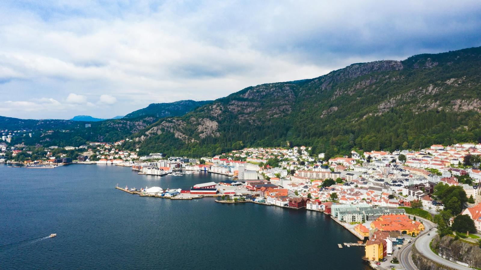 Aerial view of a coastal town beside a fjord backed by mountains