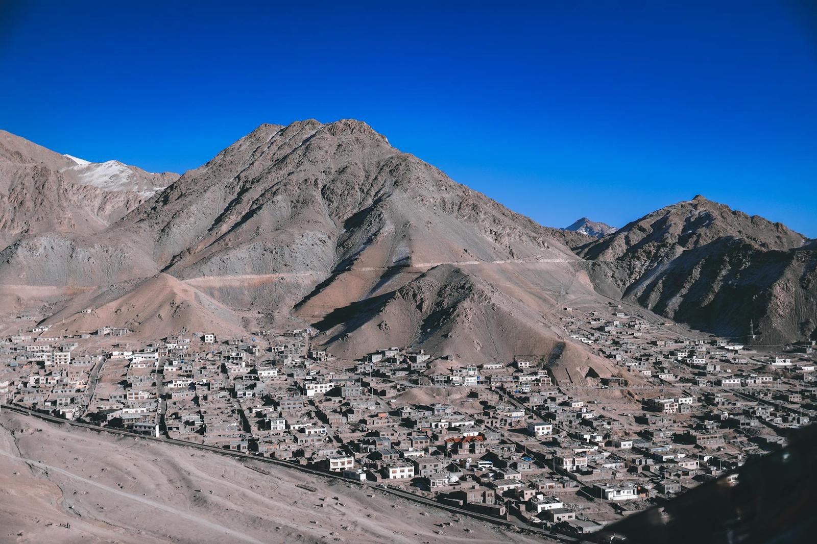 A dense hillside town spreading across a mountain slope under clear sky