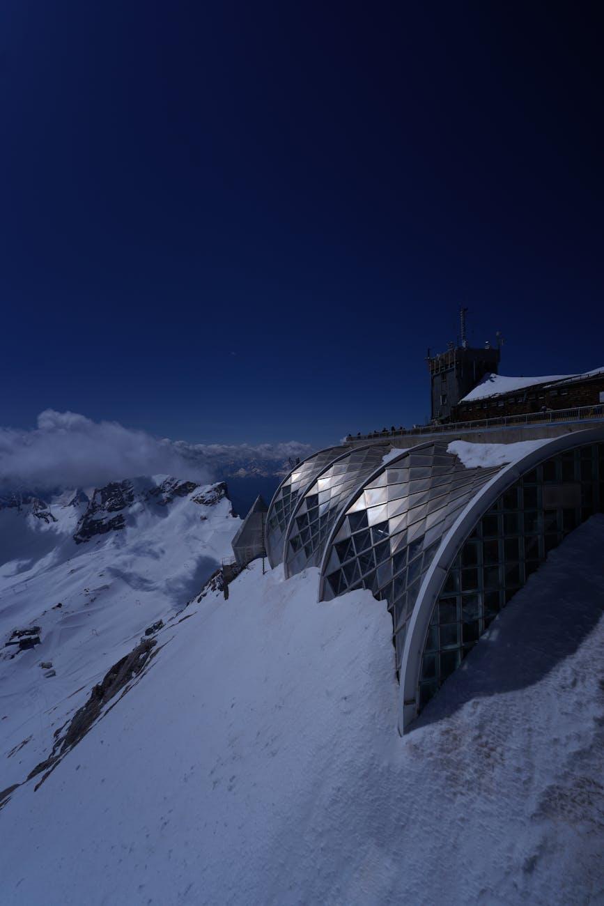 Glass-domed mountain station overlooking a sea of snow at dusk