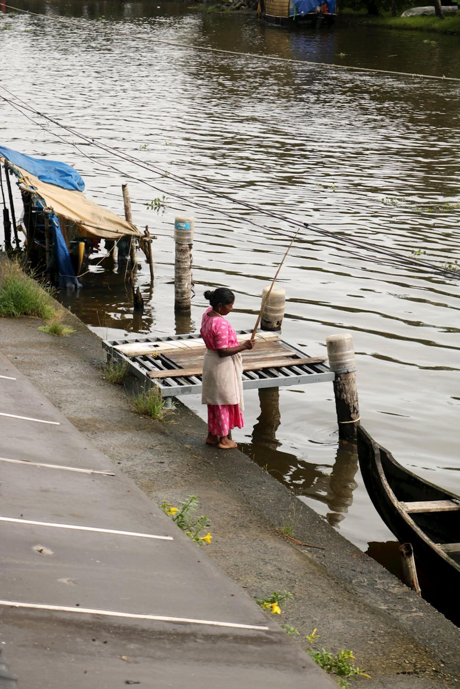A woman fishing on a dock in the peaceful Alappuzha backwaters, Kerala, India