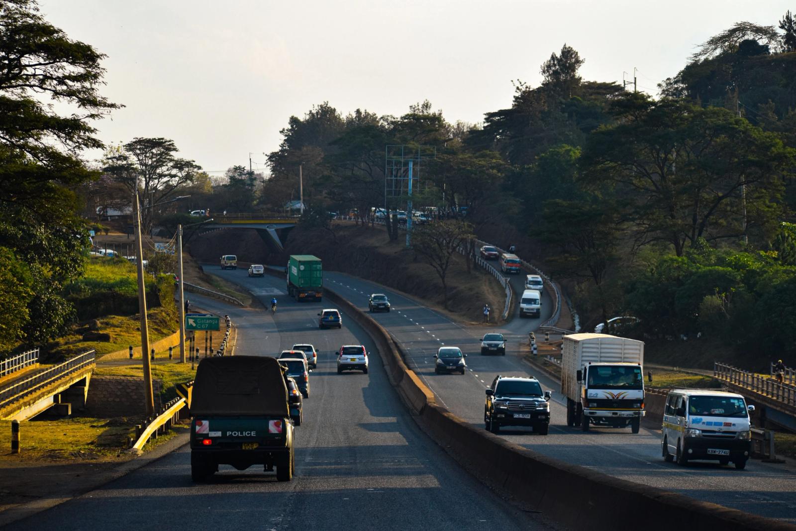 Dense traffic on a Nairobi highway surrounded by lush greenery during the day