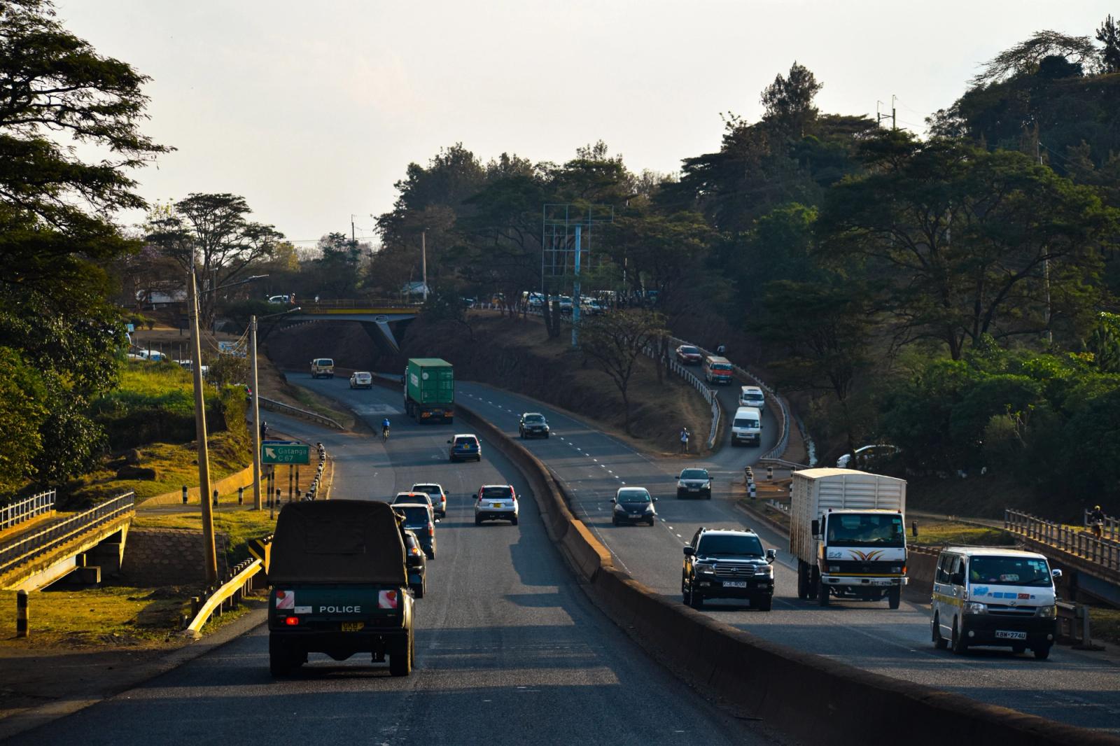 Dense traffic on a Nairobi highway surrounded by lush greenery during the day