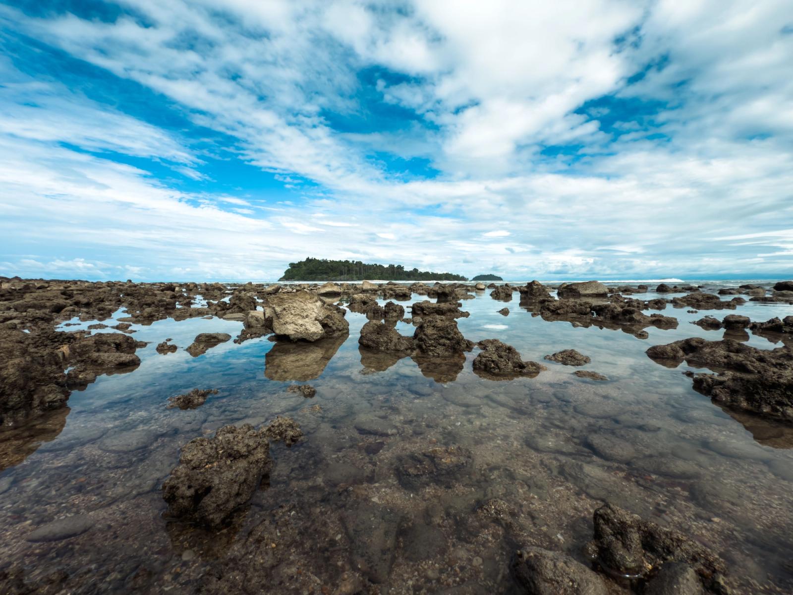 A breathtaking view of a rocky beach with clear waters and blue sky in Thailand