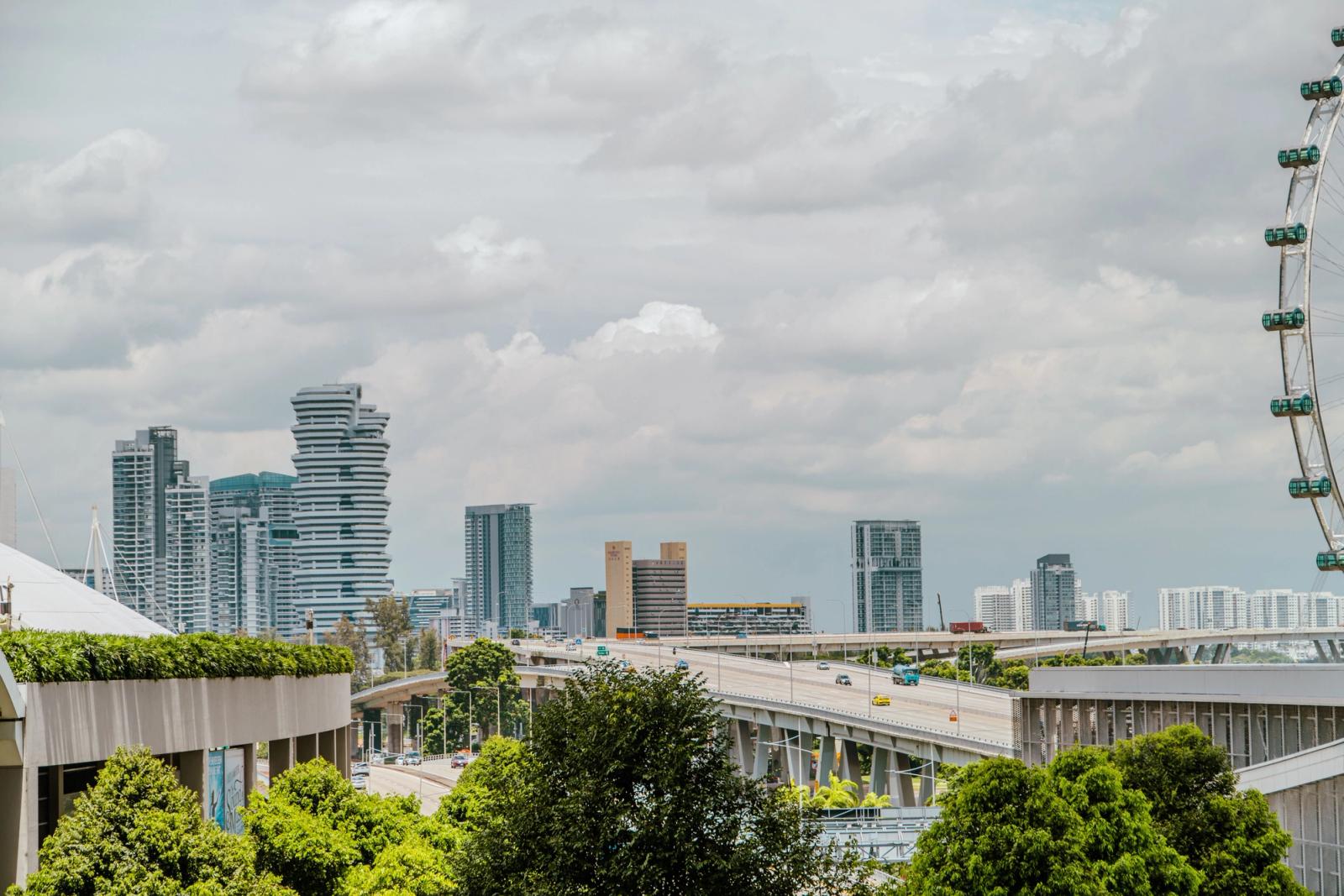 A vibrant cityscape featuring modern skyscrapers and a Ferris wheel under a cloudy sky