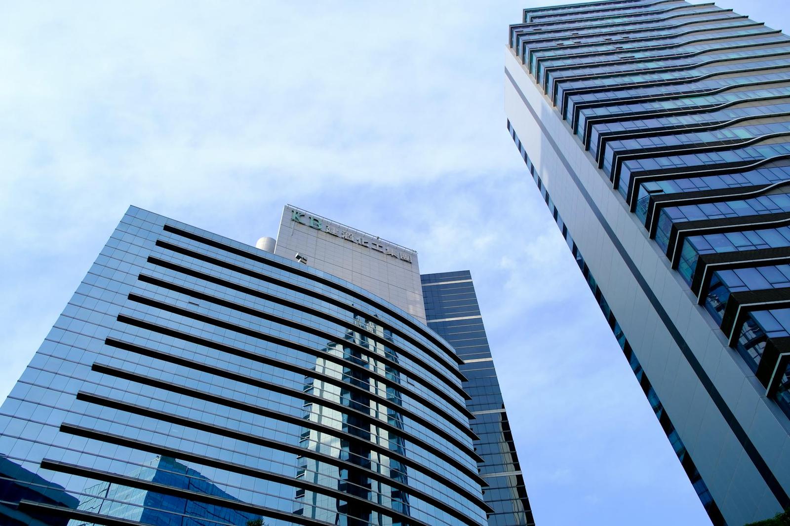 Looking up at glass skyscrapers against a bright sky
