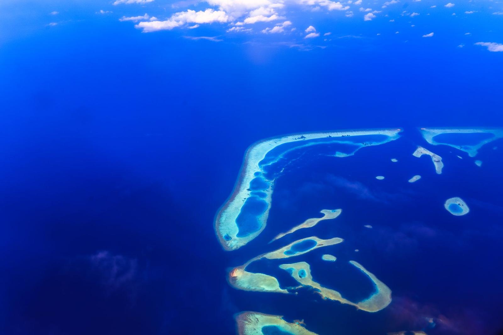 Aerial view of scattered reef formations in deep blue ocean