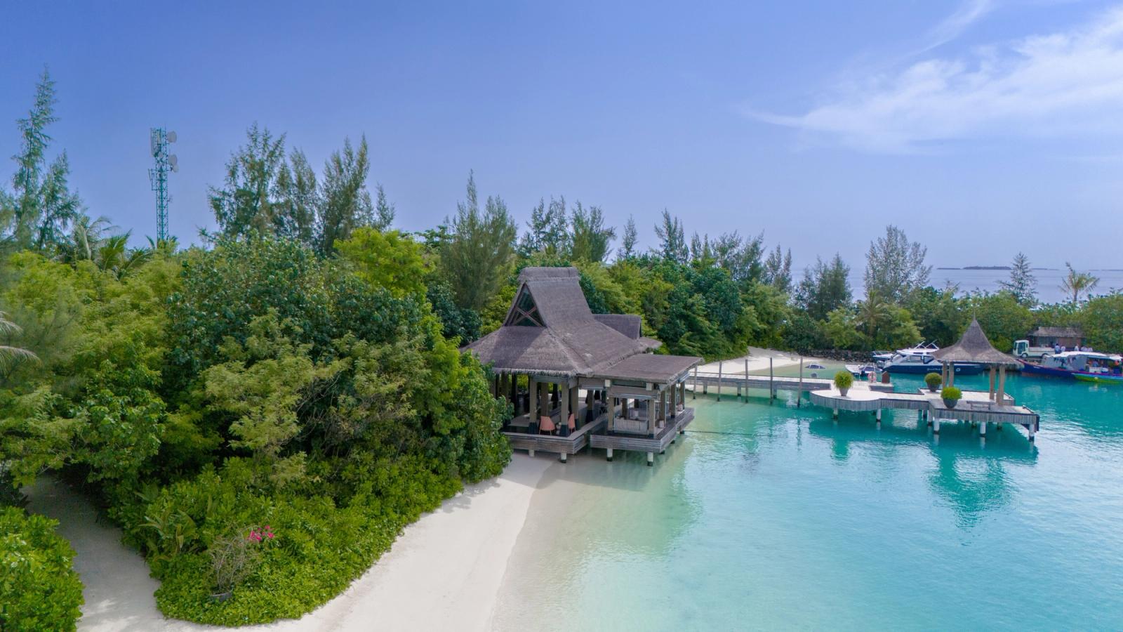 Tranquil beachside resort with a pier in Kaafu Atoll, Maldives, under clear skies