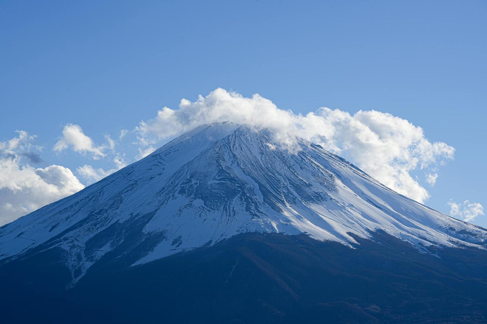 Close-up of Mount Fuji's snow-streaked summit wreathed in cloud