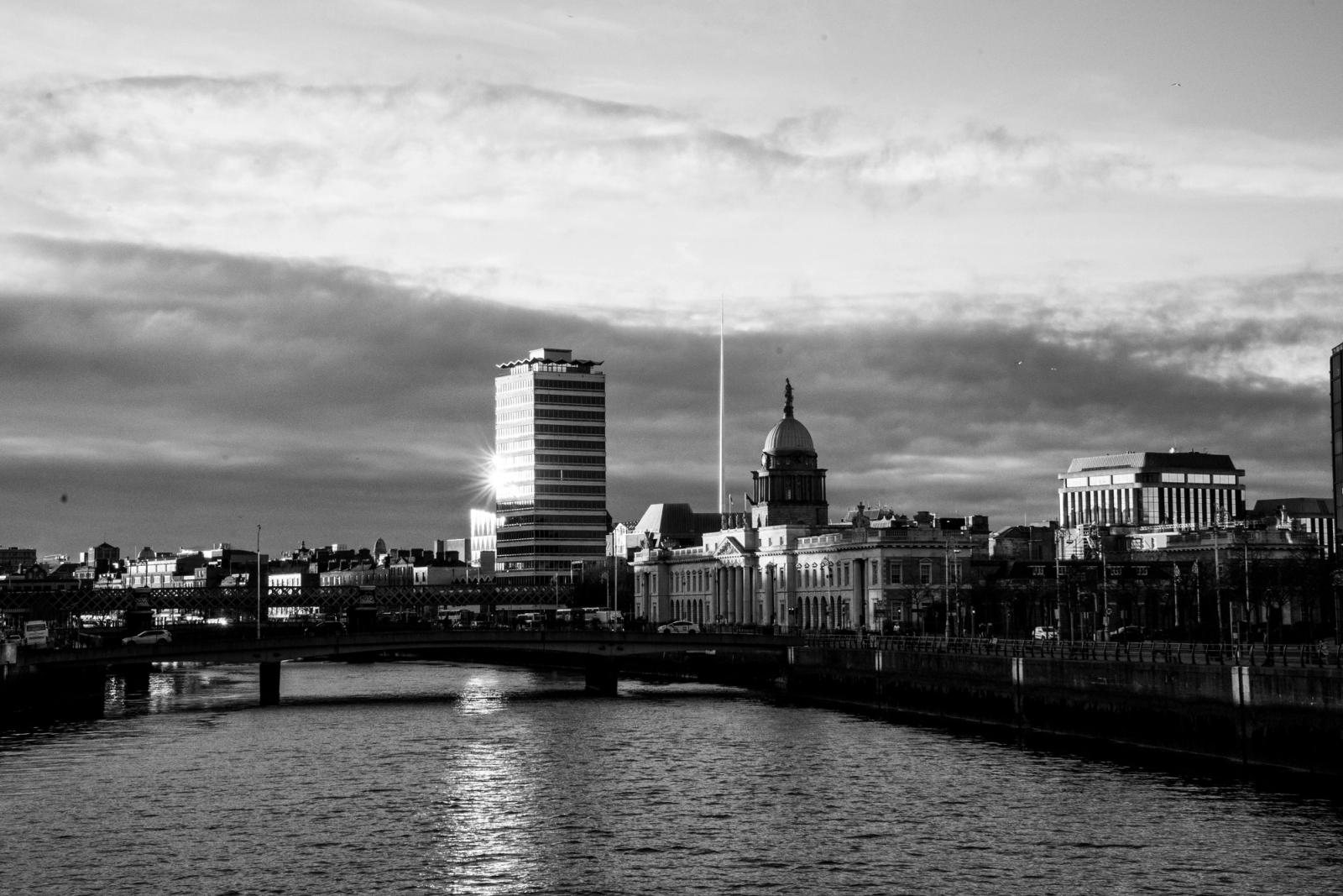 A stunning black and white cityscape of Dublin with a river view and dramatic clouds
