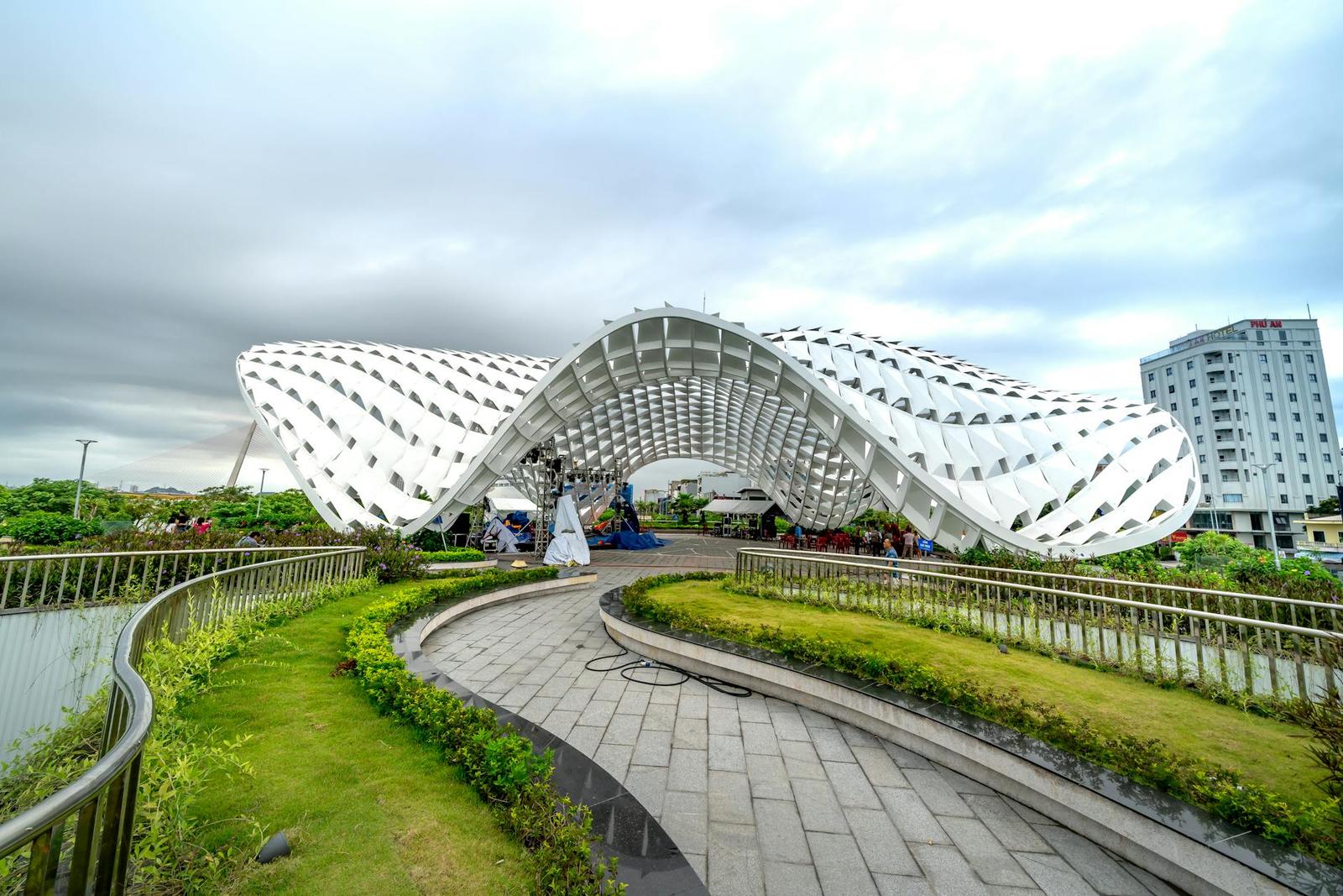 Striking modern architectural structure in Vietnam park with green walkways and urban backdrop