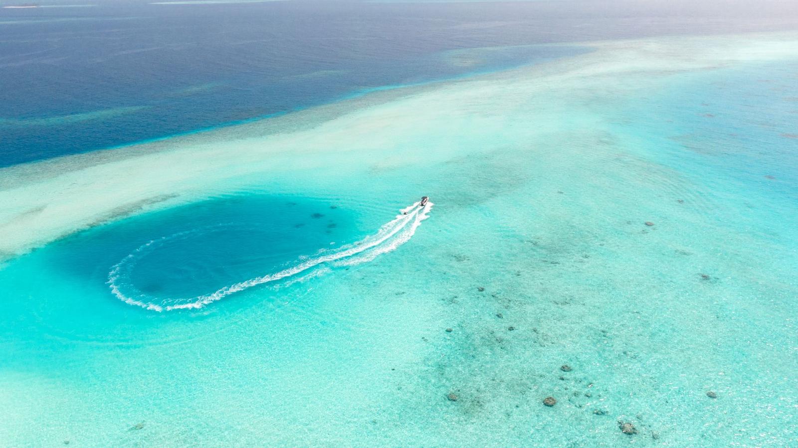 Aerial view of a jet ski carving a loop through a lagoon