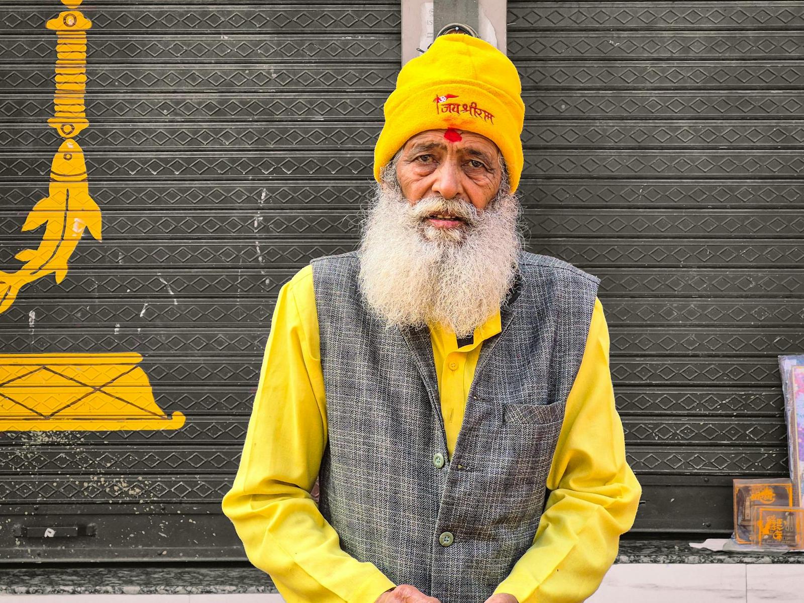 Elderly man with a long white beard wearing a yellow turban and kurta