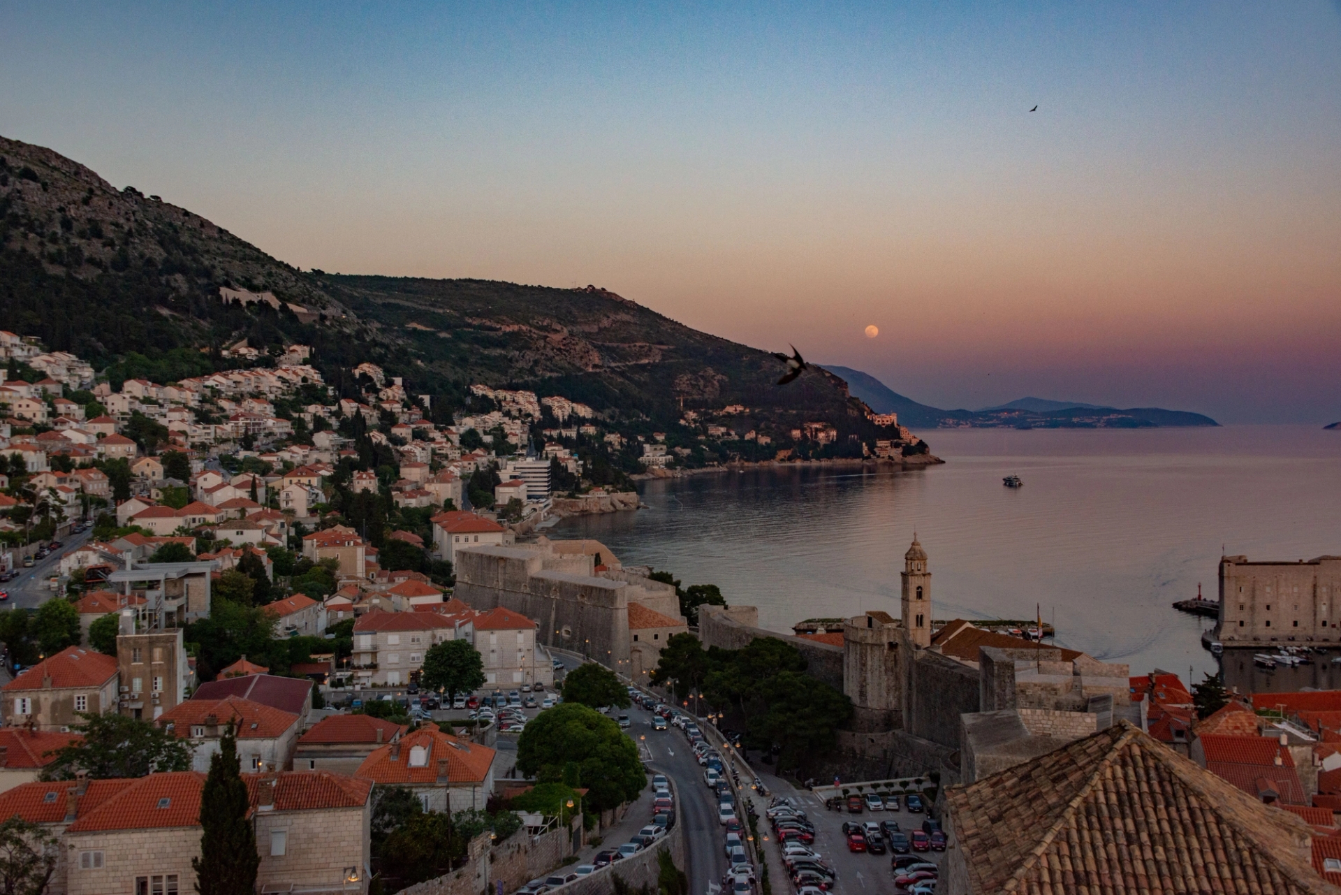 Stunning aerial capture of Dubrovnik's coastal cityscape at sunset, showcasing its historic architecture and Adriatic seascape