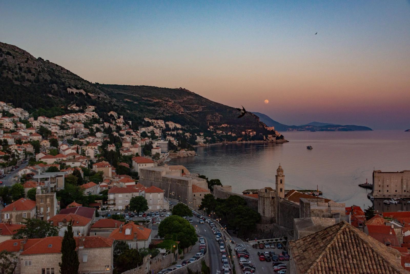 Stunning aerial capture of Dubrovnik's coastal cityscape at sunset, showcasing its historic architecture and Adriatic seascape