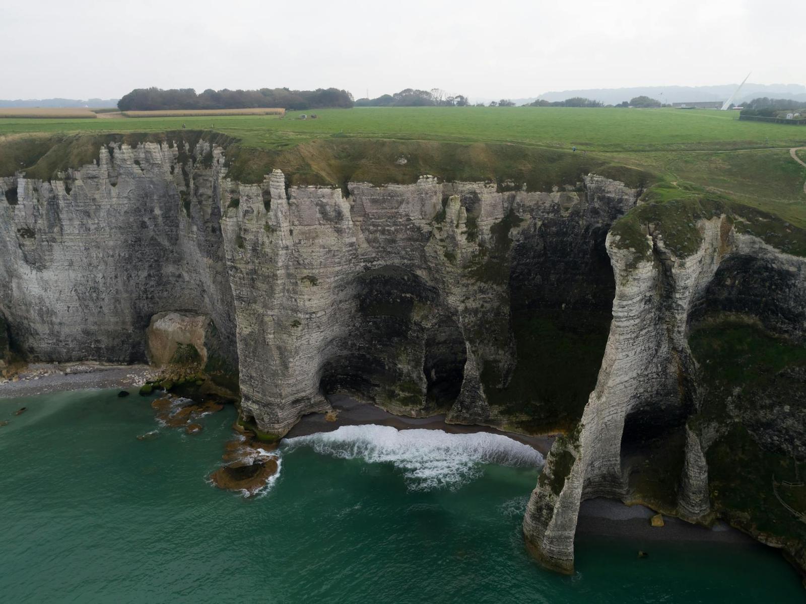 Aerial view of jagged white sea cliffs carved into arches and stacks