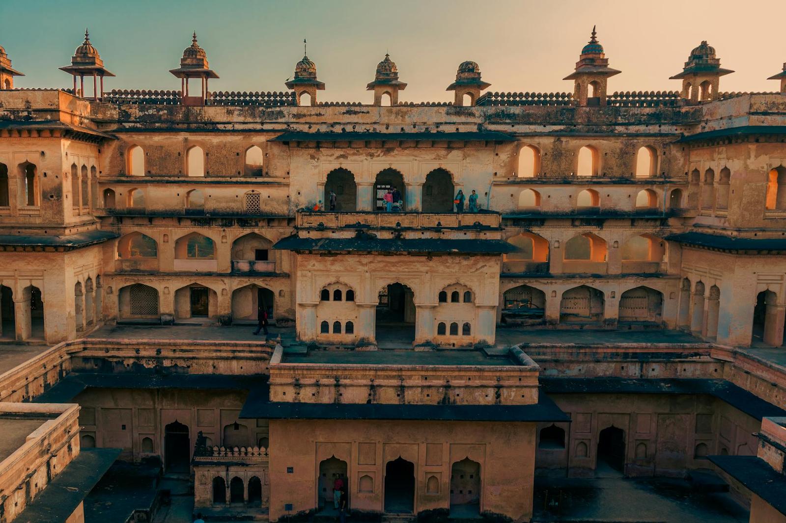 Aerial view of a sandstone fort palace with arched courtyards at sunset