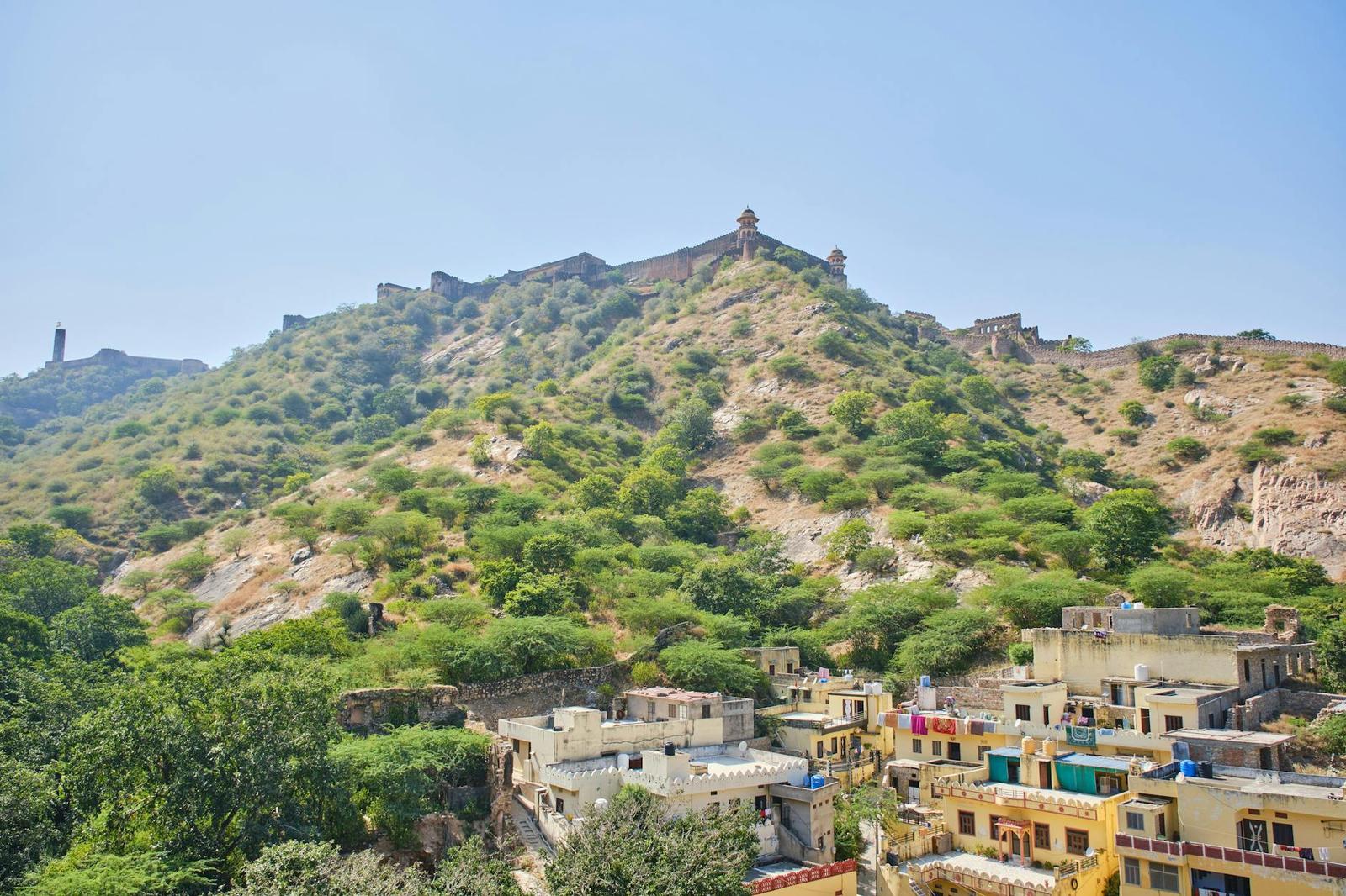 A hilltop fort wall snaking above a colourful hillside neighbourhood