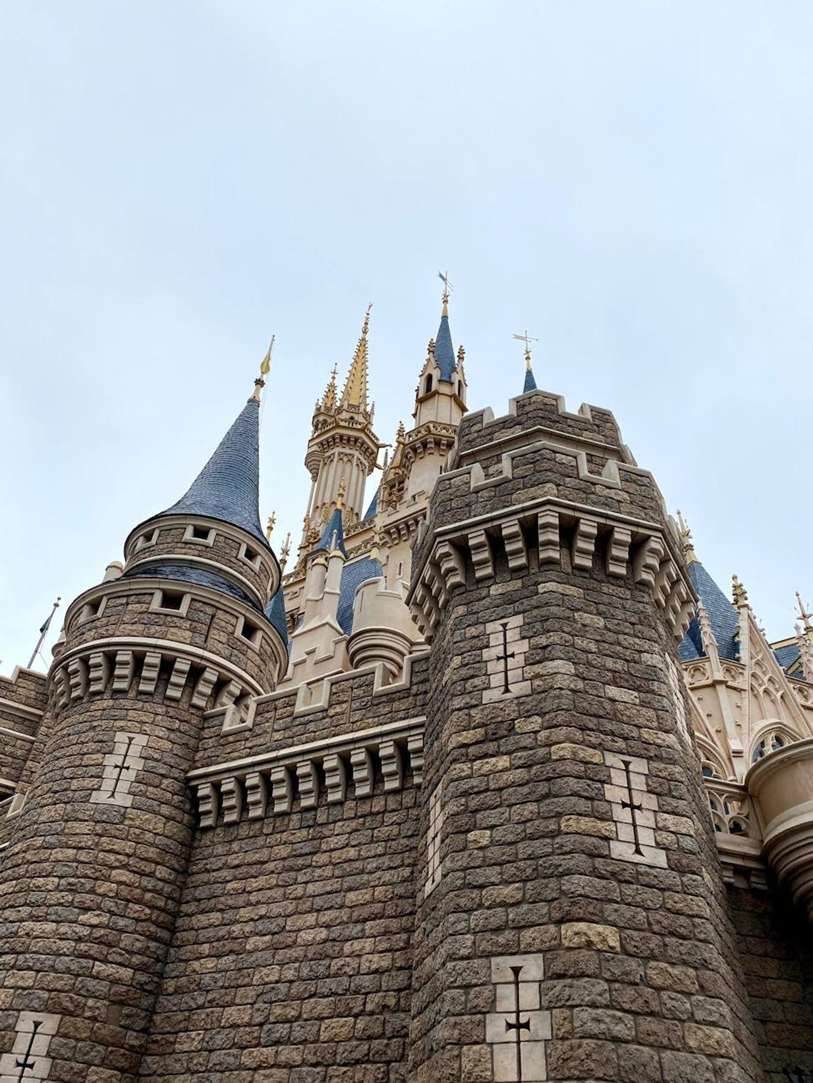 Close-up of a stone castle's turrets and spires against a pale sky