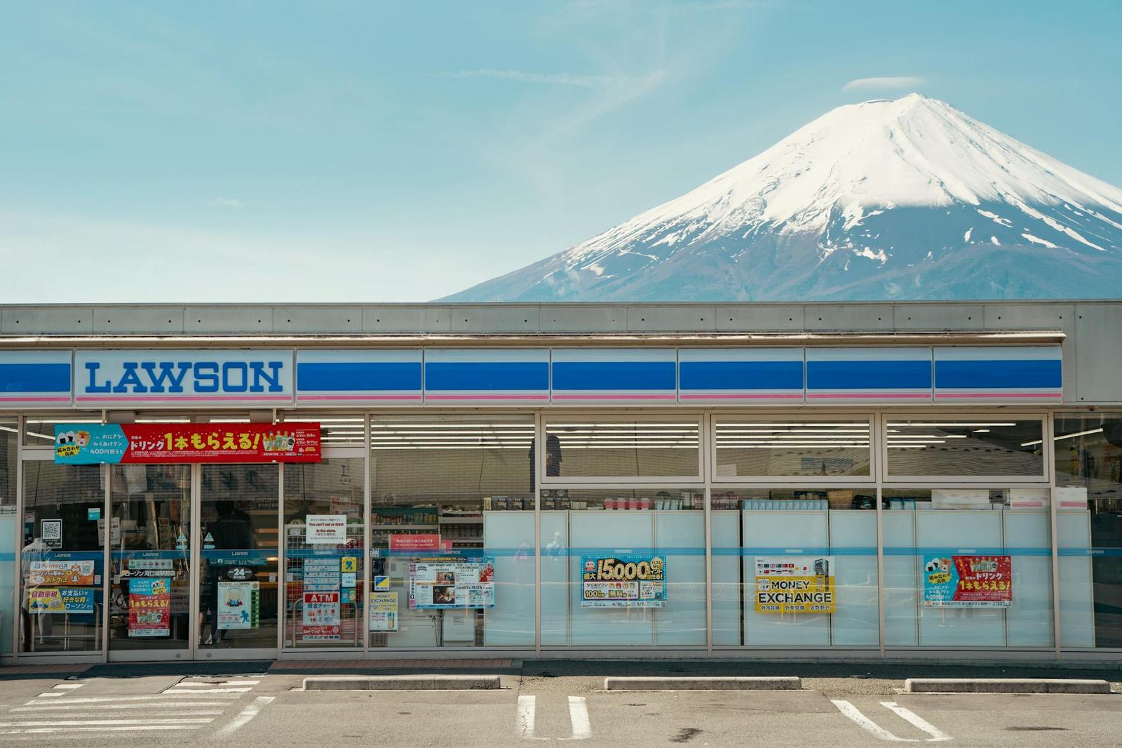 A convenience store storefront with Mount Fuji's snow-capped peak behind