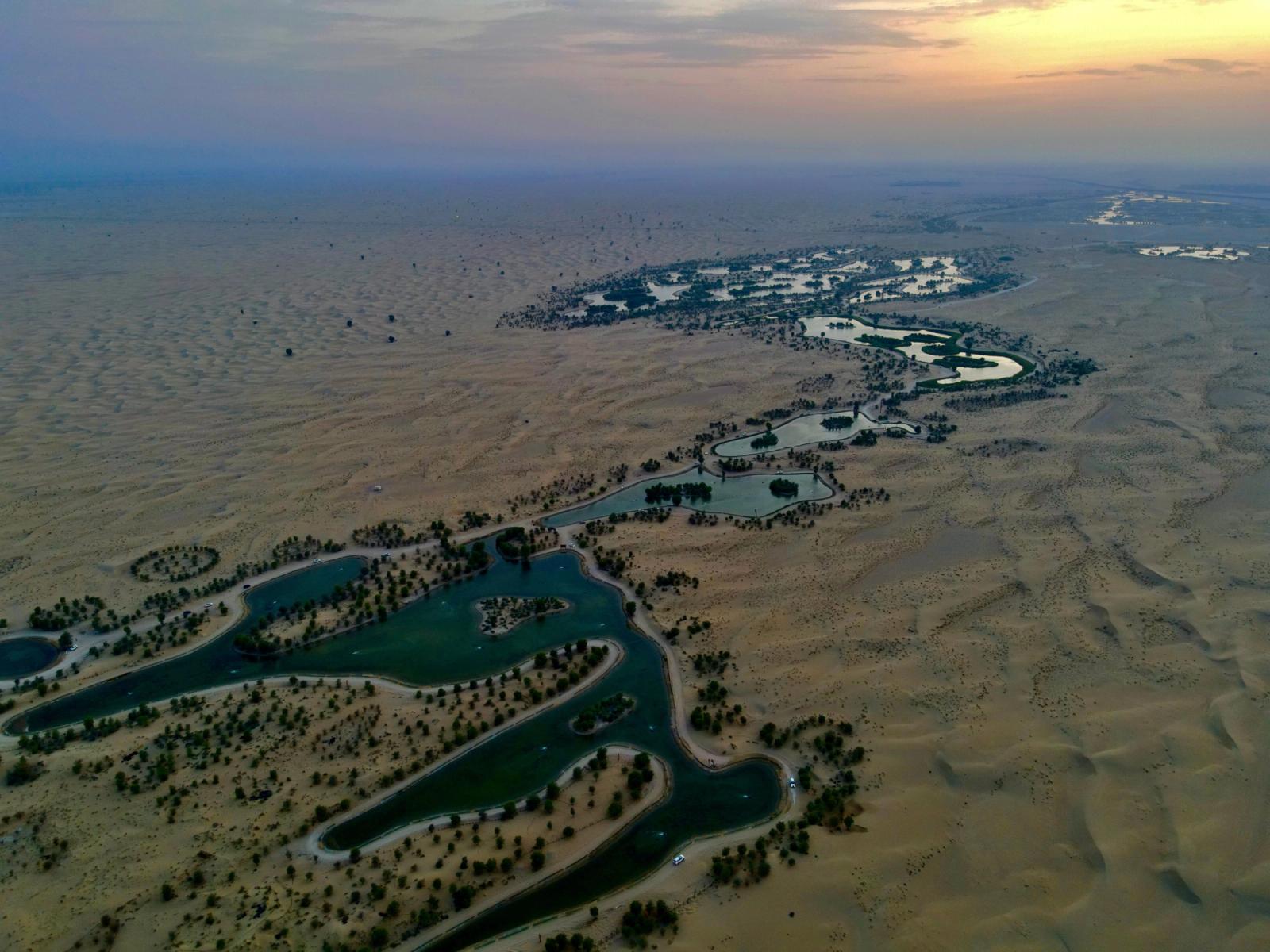 Breathtaking aerial view of the scenic Al Qudra Lake in Dubai at sunset, with winding waterways