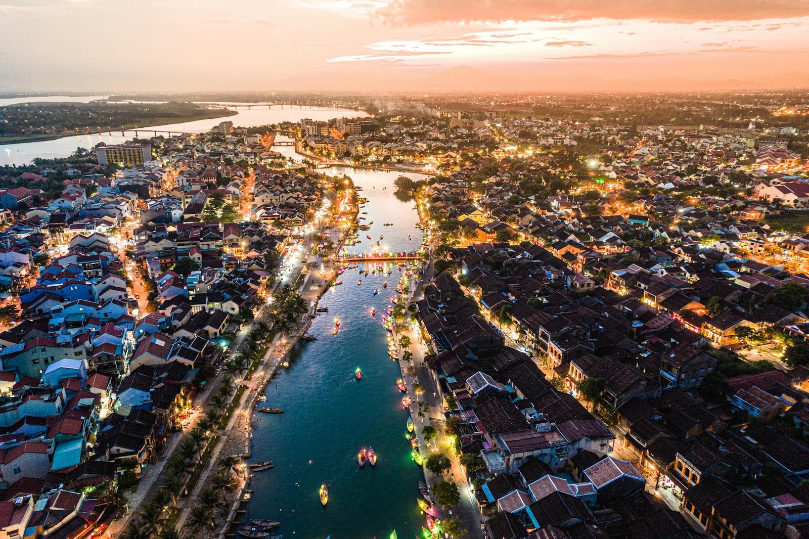 Aerial view of a riverside old town lit up along a canal at dusk