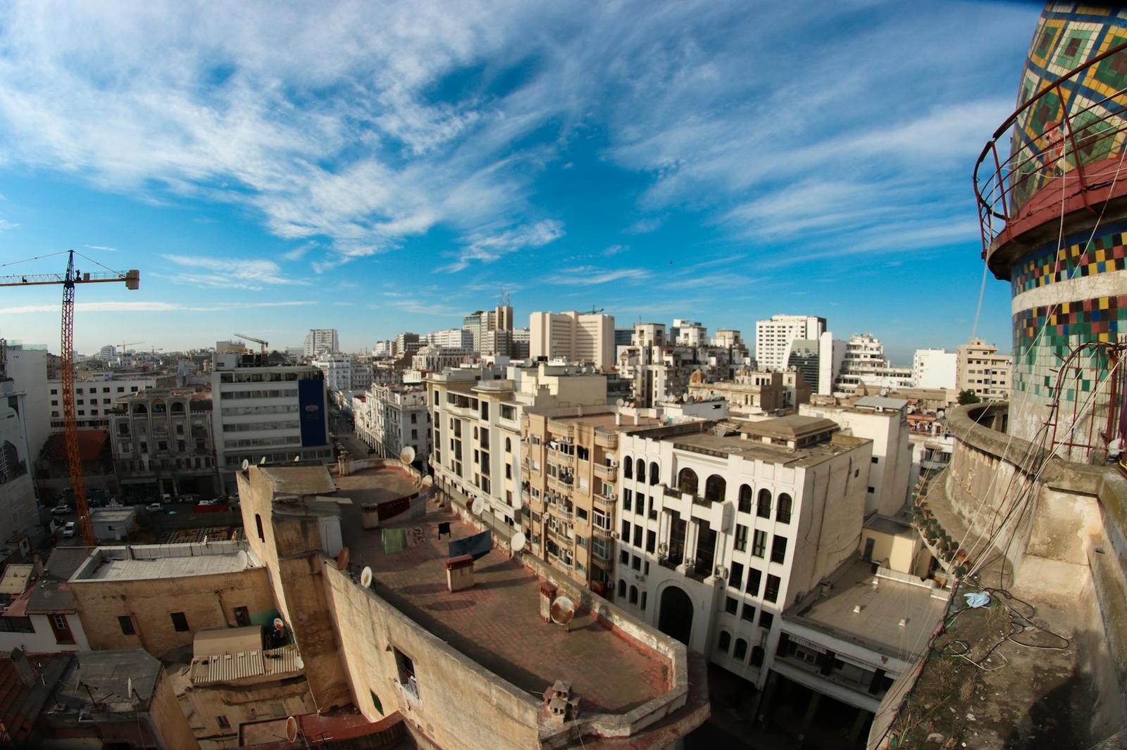 Rooftop panorama of a dense city skyline under a sweeping blue sky
