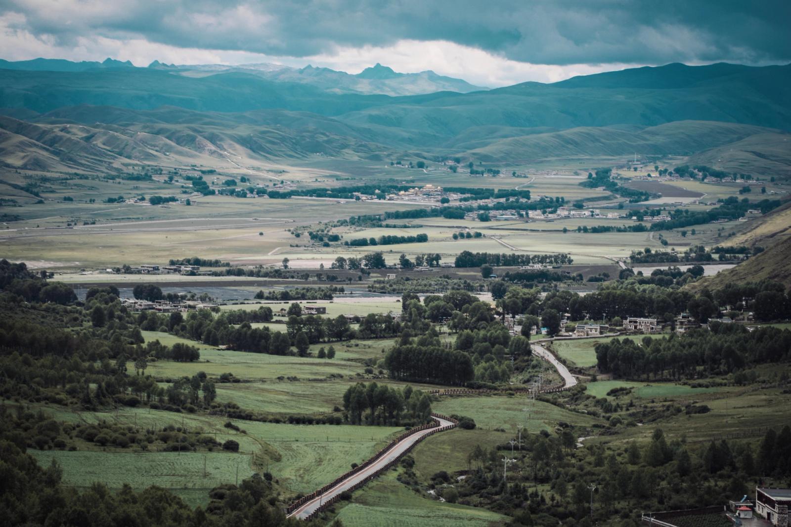 A breathtaking panorama of a lush green valley with distant mountains, ideal for travel and nature enthusiasts