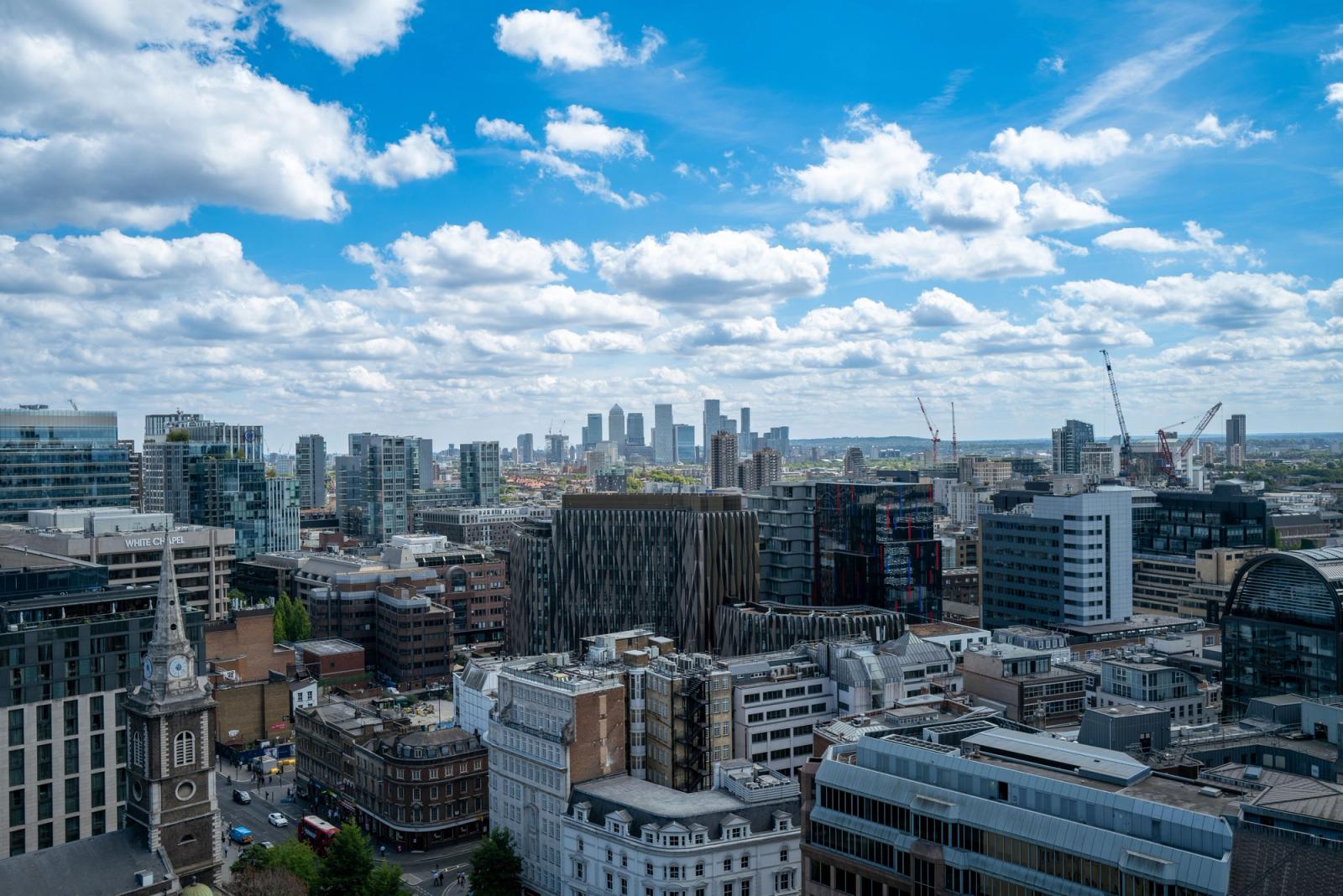 Aerial view of London's modern skyline under blue sky with clouds