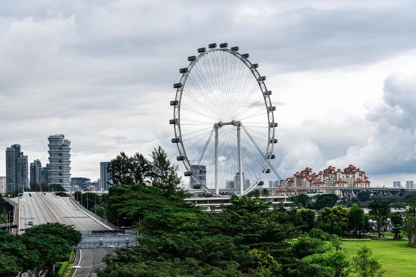 Scenic view of Singapore Flyer surrounded by greenery under a cloudy sky
