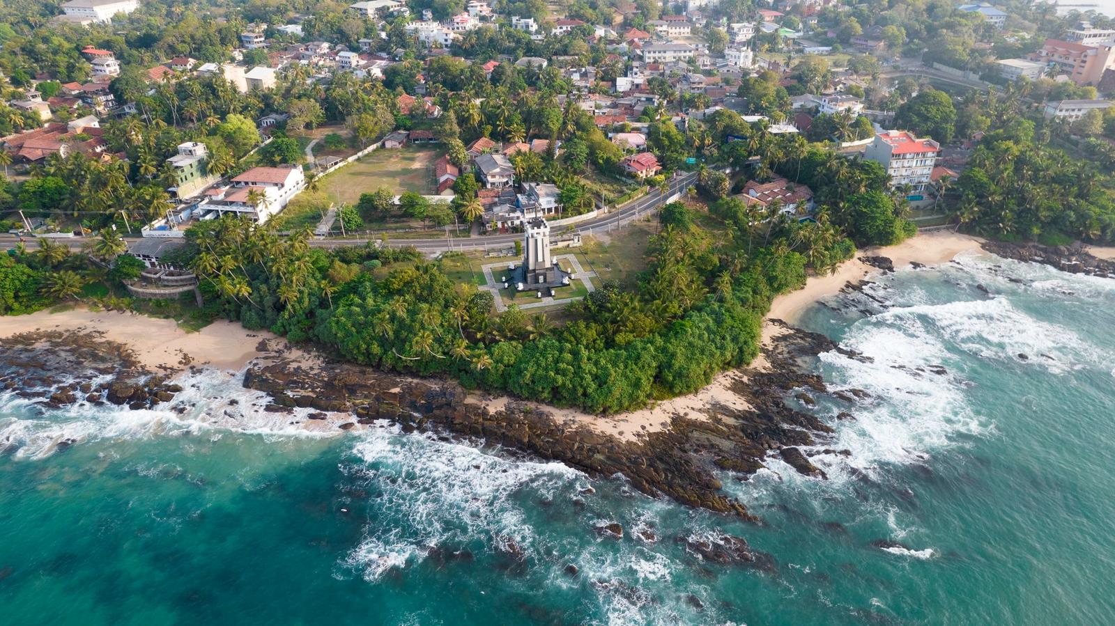 Aerial view of a coastal town headland with a lighthouse among trees