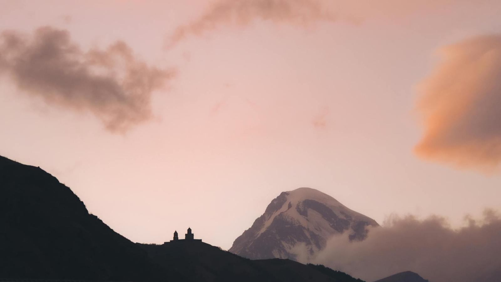 Stunning silhouette of Gergeti Trinity Church with Mount Kazbek at sunrise in Georgia