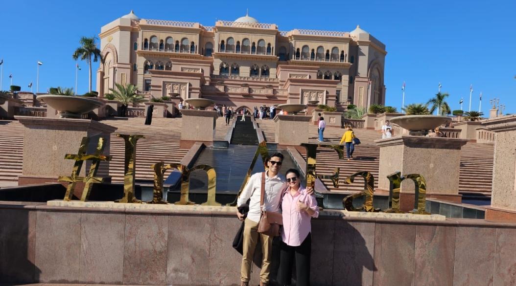 A couple posing together in front of a decorative sign