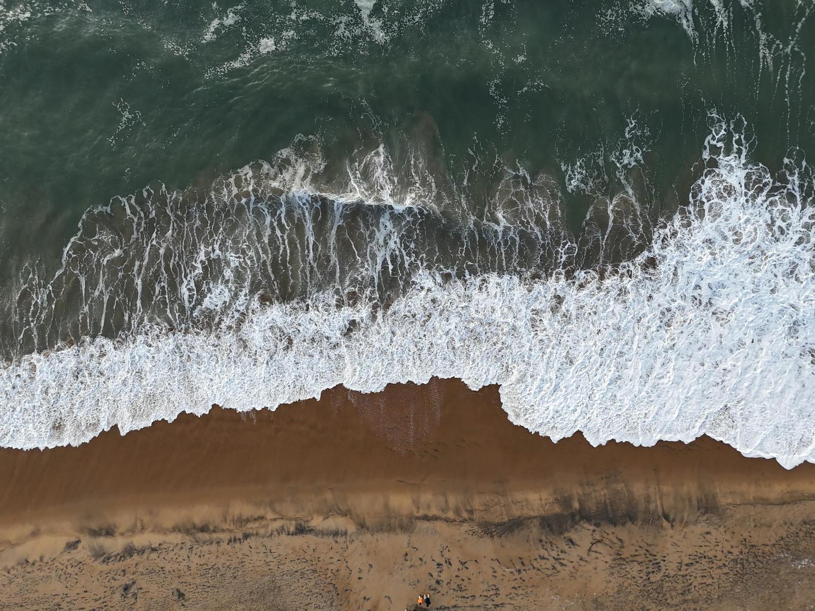 Aerial view of foamy waves breaking on a sandy shore