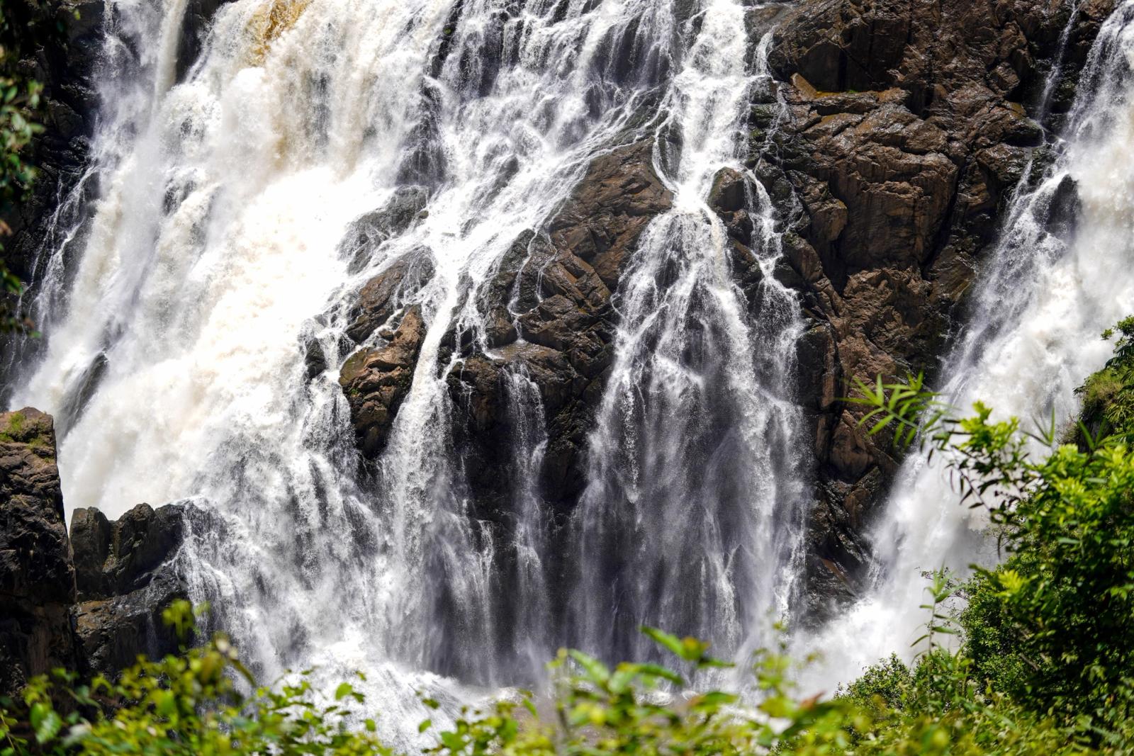 Powerful waterfall flowing over rugged rocks, surrounded by lush greenery, creating a dramatic scene