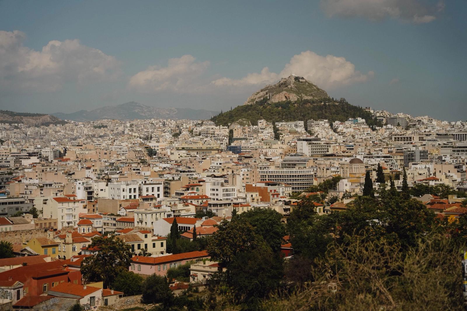 A stunning view of Athens cityscape with iconic Lycabettus Hill under a partly cloudy sky