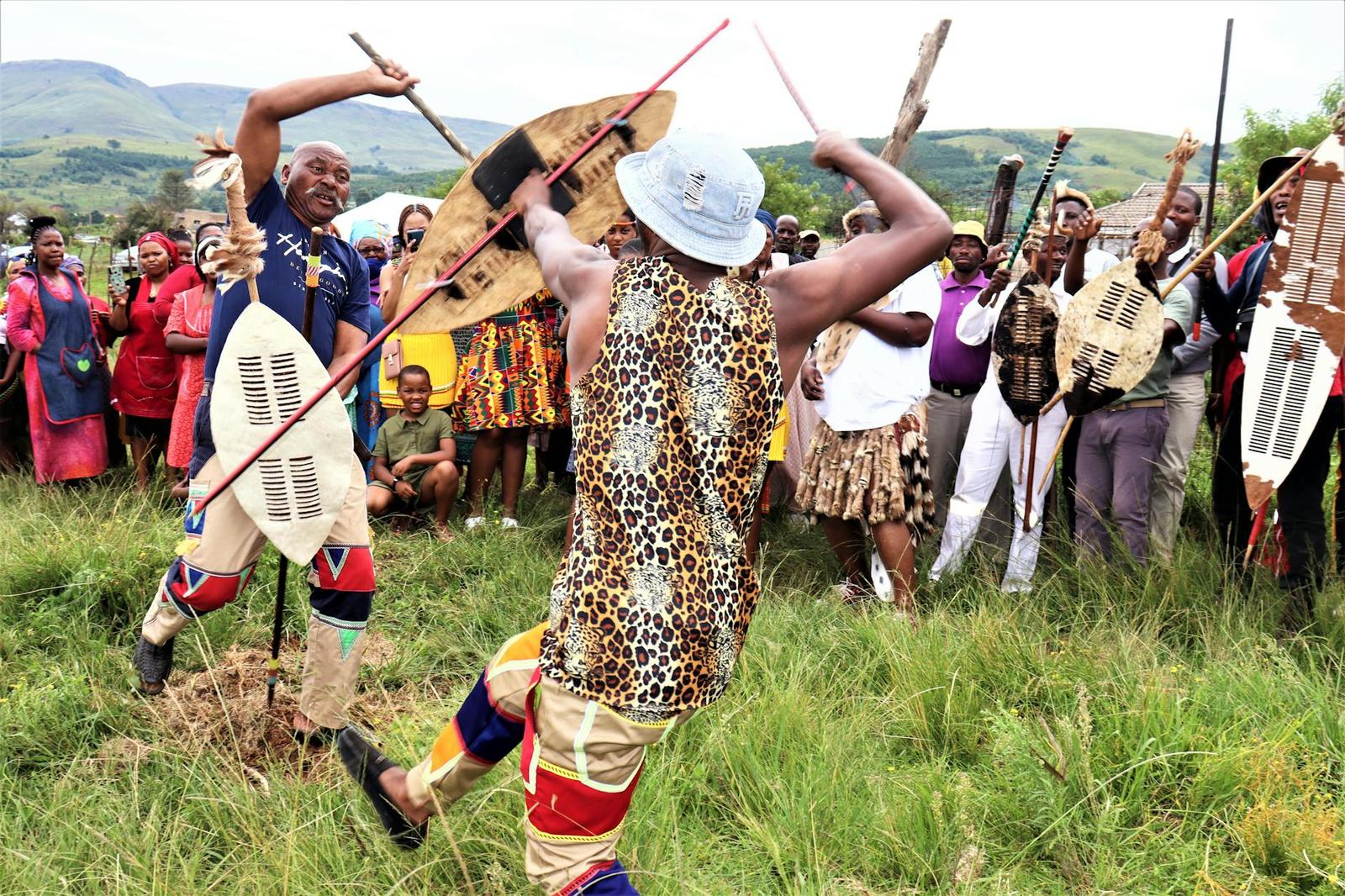 Traditional dancers in animal-print costumes performing with shields and spears