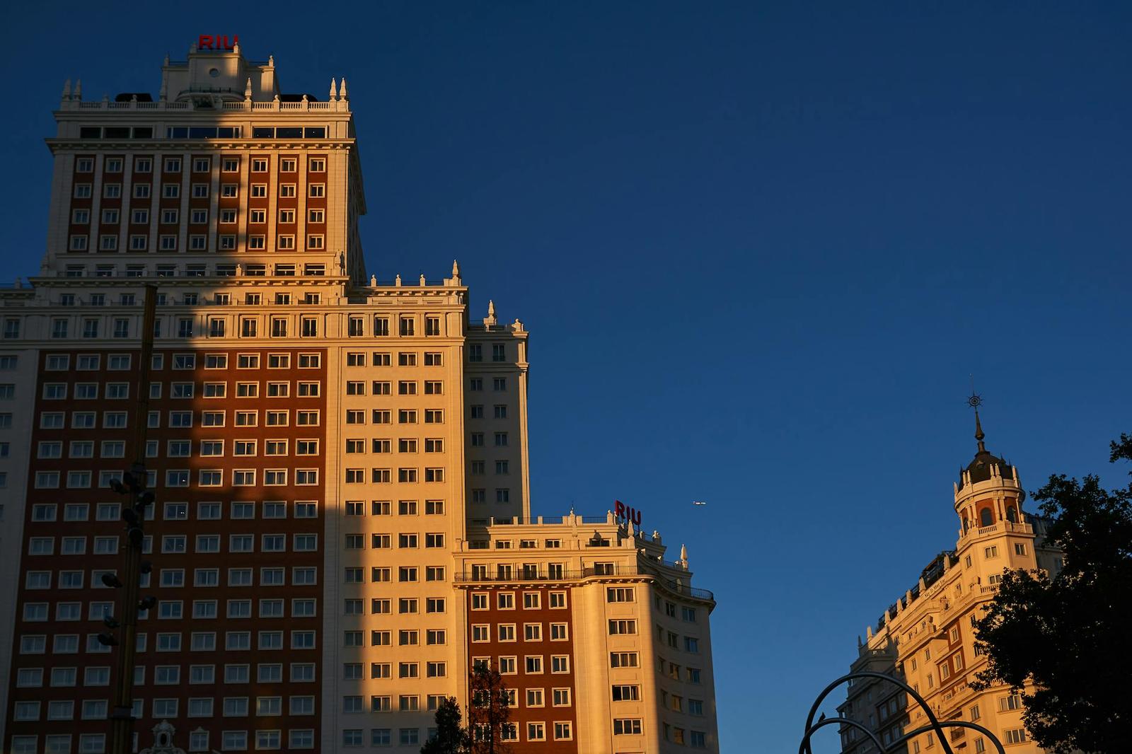 Ornate high-rise buildings catch golden light against a deep blue sky
