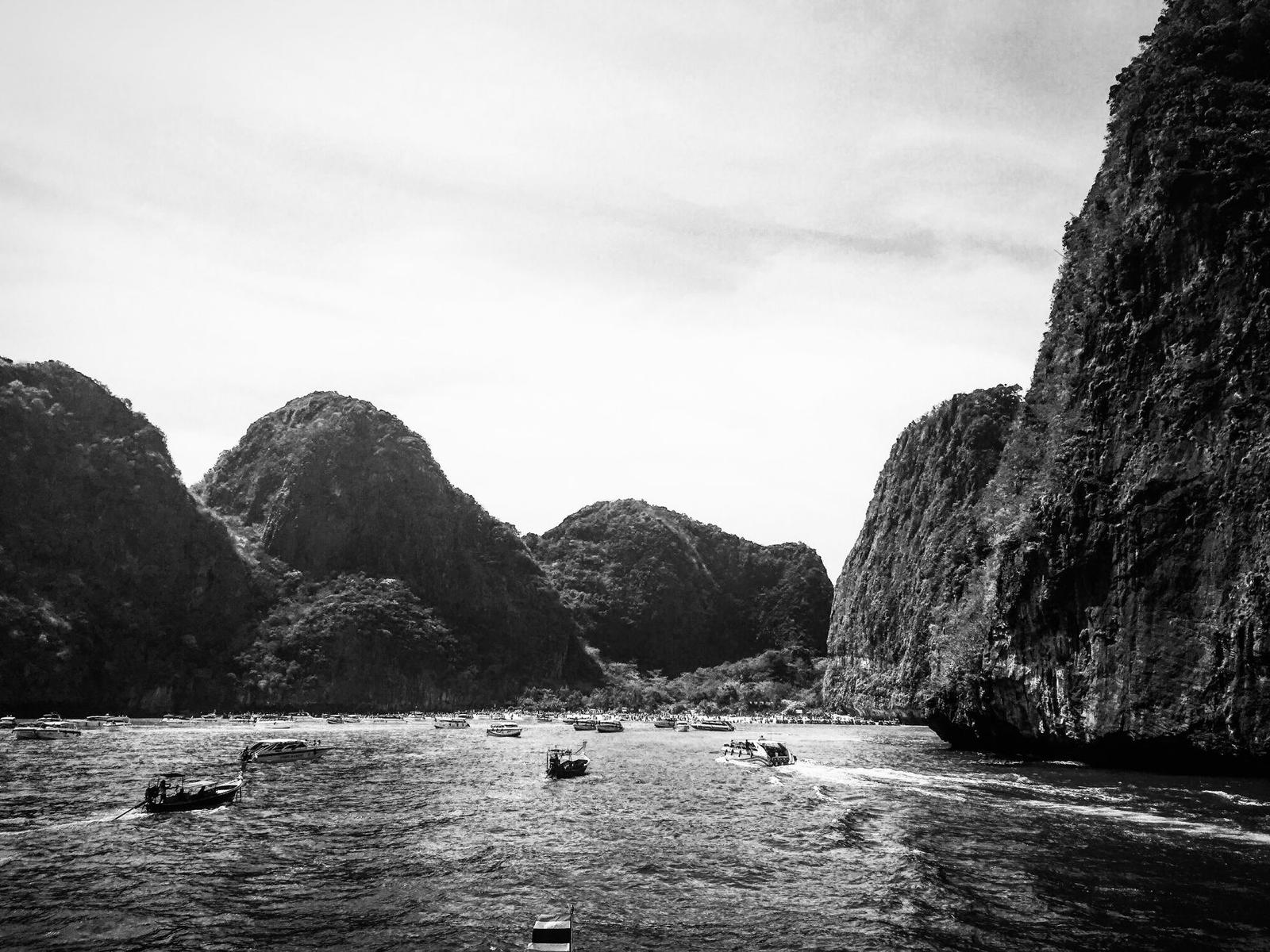Majestic limestone cliffs and boats in vibrant Thailand, captured in black and white