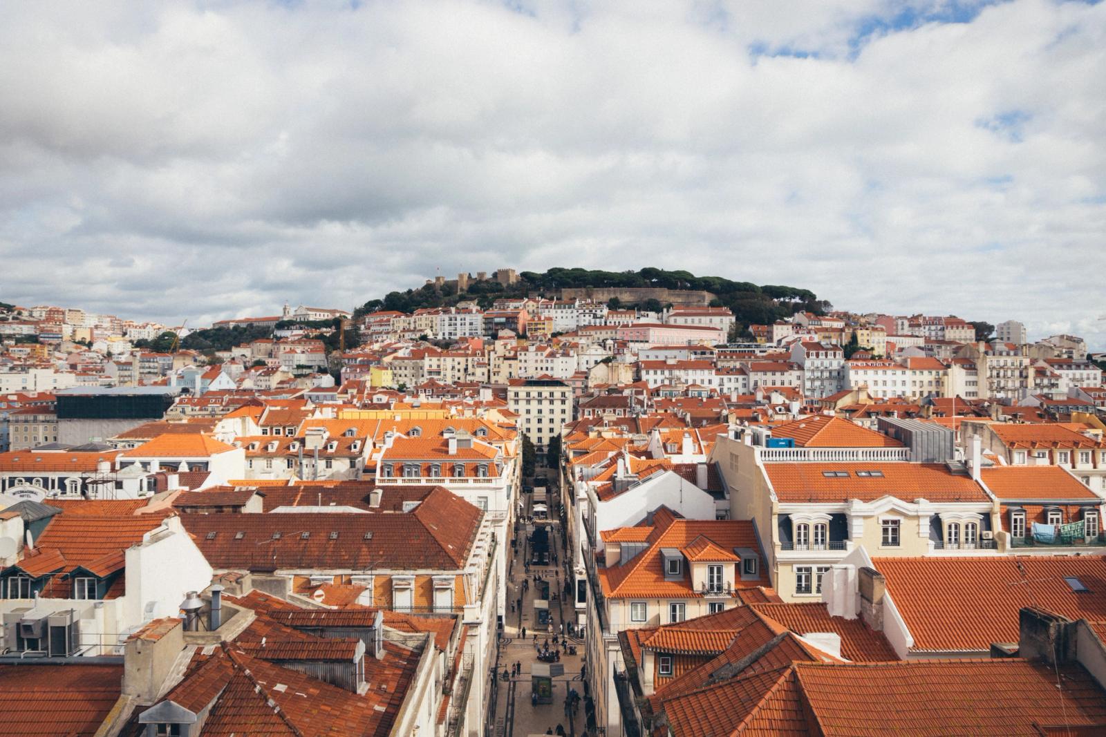 Aerial view of Lisbon's red rooftops and historic architecture under a cloudy sky
