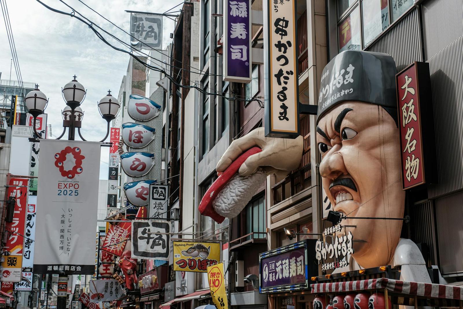 A busy shopping street crowded with oversized illuminated signage and mascots