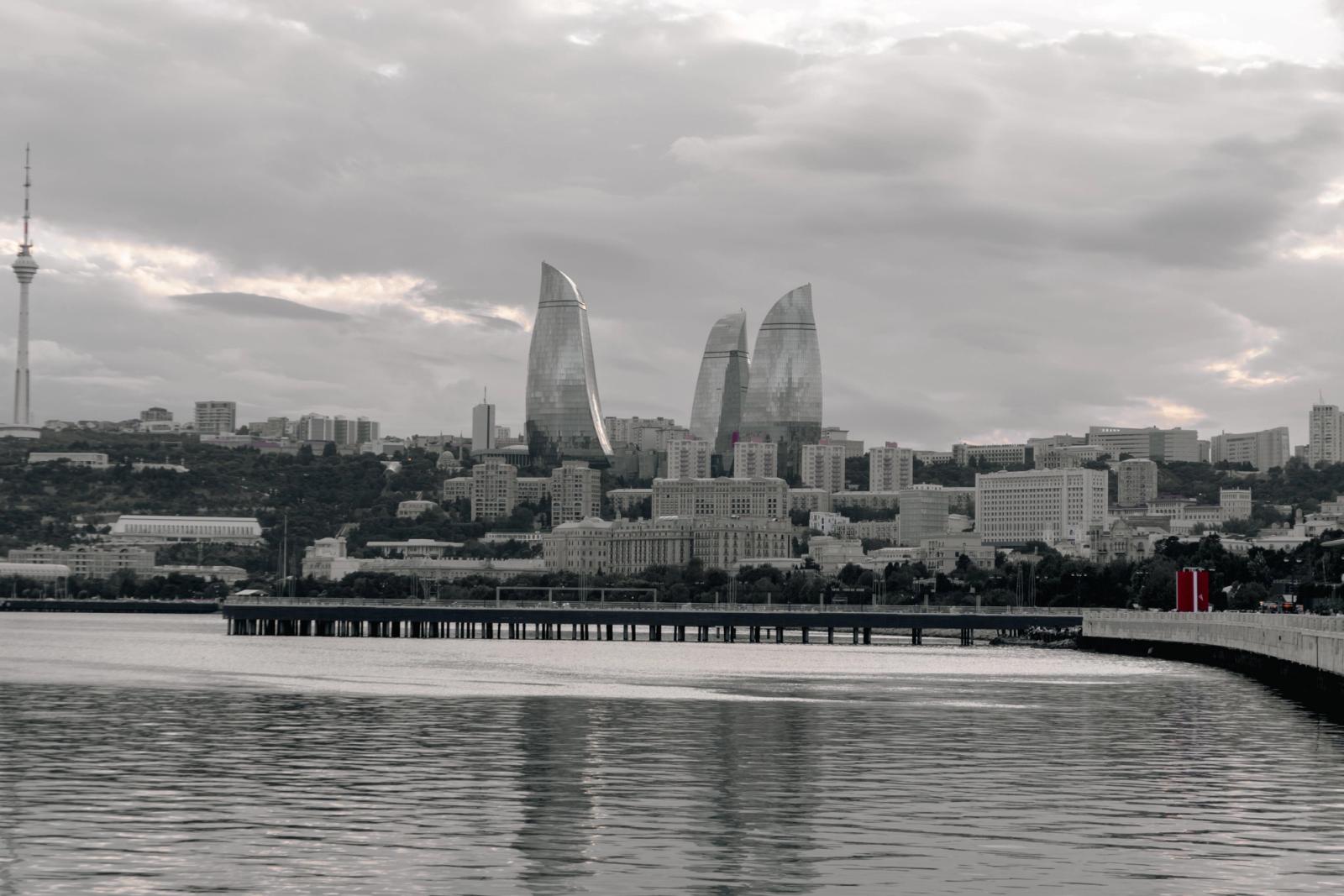The striking silhouette of Baku's Flame Towers against a dramatic sky, viewed from the Caspian Sea