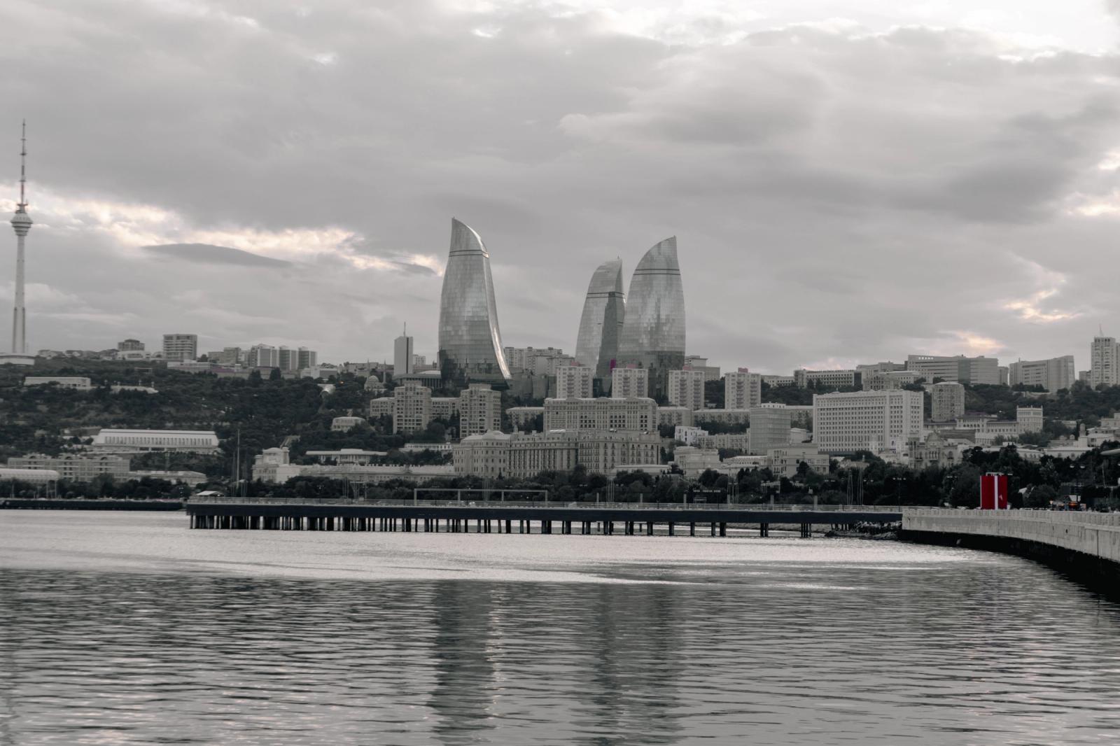 The striking silhouette of Baku's Flame Towers against a dramatic sky, viewed from the Caspian Sea