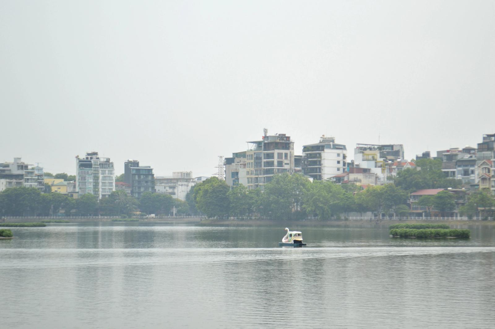 Tranquil lake with a swan paddle boat against a modern city skyline backdrop