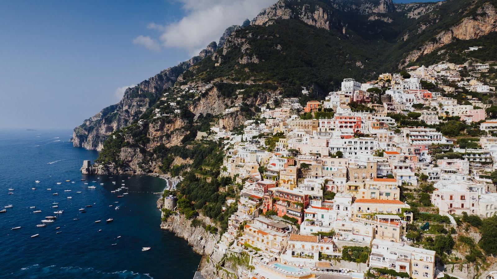 A cliffside town of pastel buildings above a blue coastline